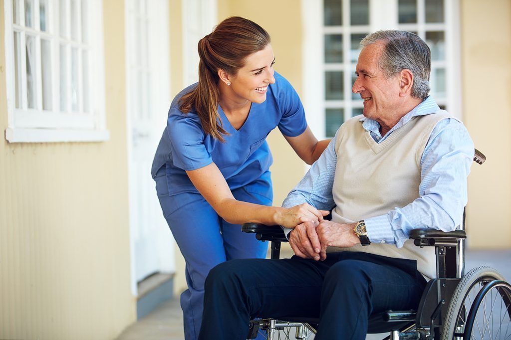 A care professional beside an older wheelchair user