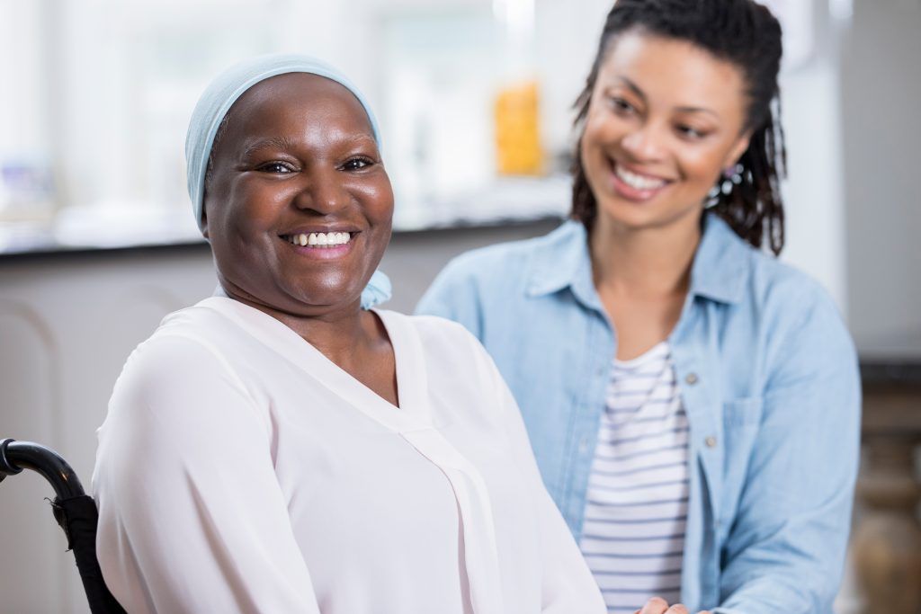 An older wheelchair user and a companion smiling together indoors