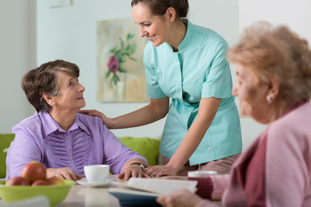 A care worker talking with an older adult at a home table